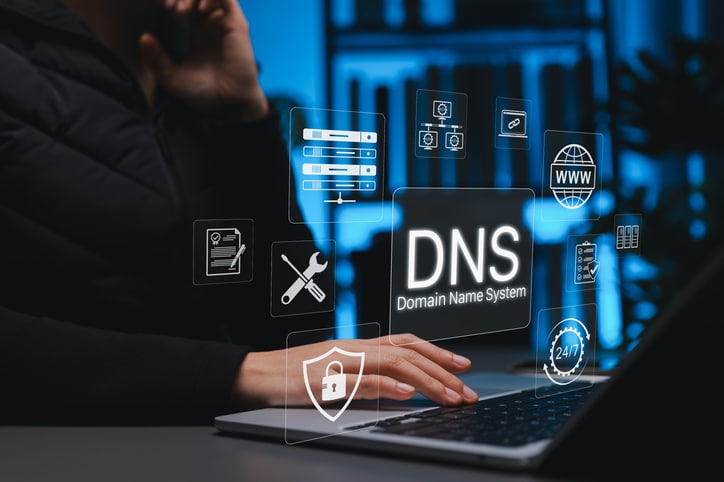 Person using a laptop in a server room with digital DNS, web, security, and network icons overlaid.