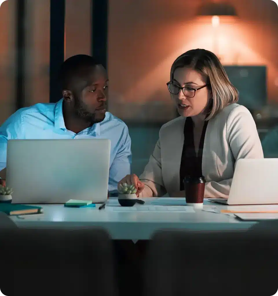 Two colleagues reviewing security information together on laptops
